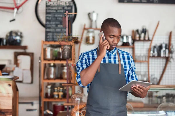 Small business owner using a phone and tablet in a shop.